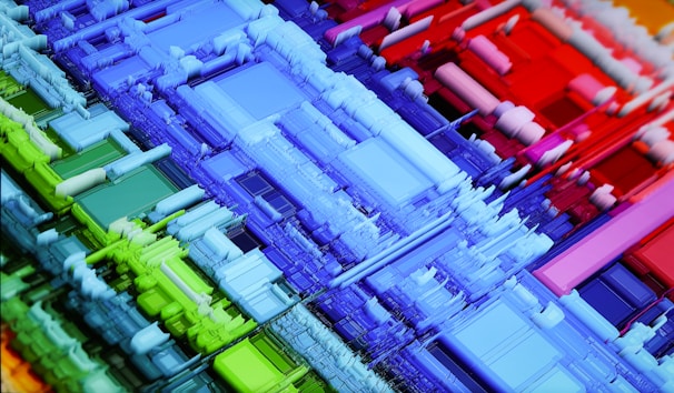 A vibrant, abstract 3D geometric structure composed of colorful blocks and layered forms. The intricate design consists of rectangles and squares in various sizes, creating a sense of depth and complexity. The colors transition smoothly from cool blues and greens on the left to warm reds on the right.