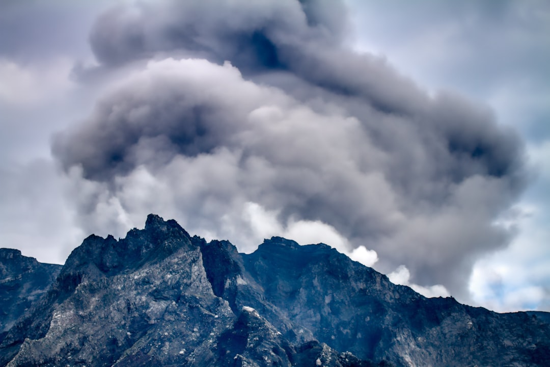 white clouds over brown and black mountain