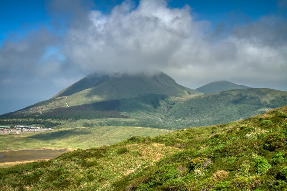 green mountain under white clouds and blue sky during daytime