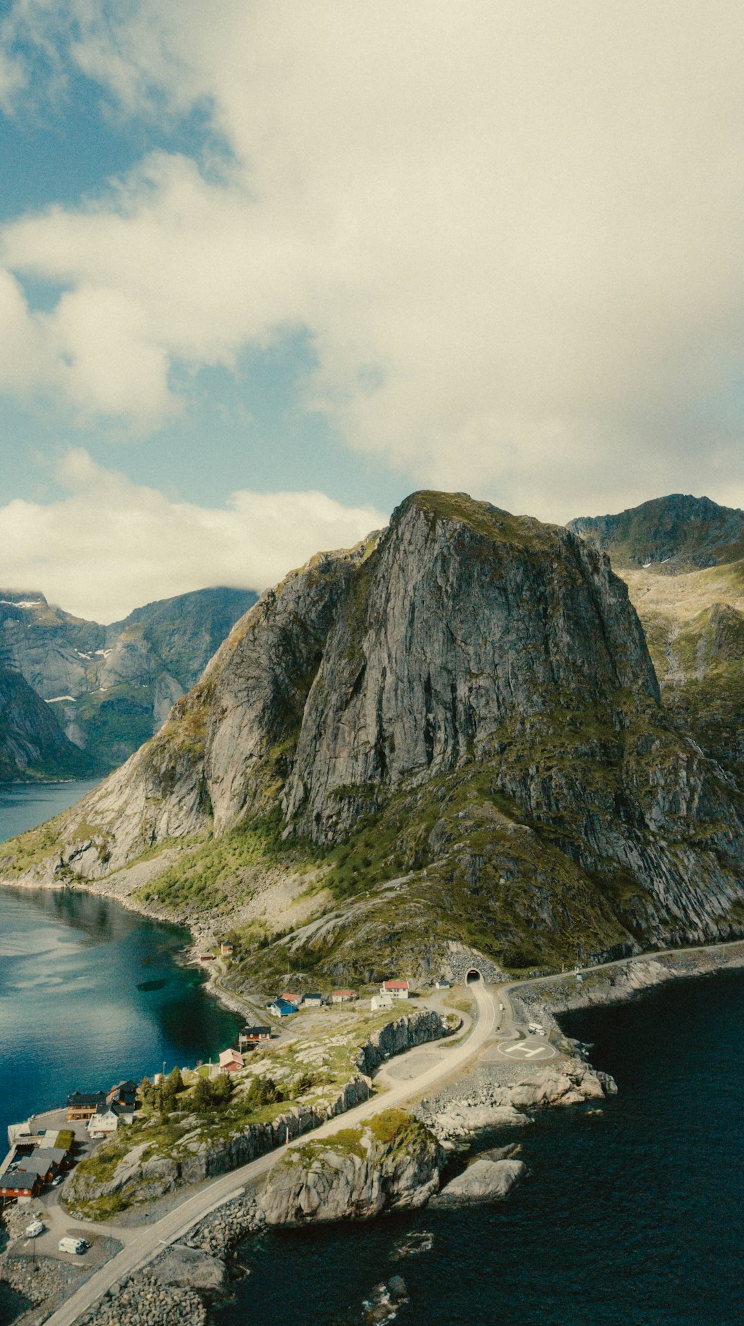 green and brown mountain beside body of water under cloudy sky during daytime