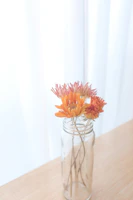 Soft peach and orange tinted jars of cream nestled among fresh botanicals with warm golden light