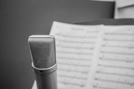 A close-up shot of a microphone and sheet music on stage.