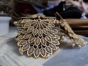 Intricate jewelry design featuring leaf-shaped patterns adorned with small, detailed embellishments. The craftsmanship includes a combination of gold and black materials, giving it an exquisite and luxurious appearance.