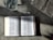 An open book with text in a language that appears to be Chinese is placed on a textured surface. There is a glass of water nearby, showing light reflections and refractions. Part of a newspaper with visible text is placed adjacent to the book, adding a sense of casual reading or study.