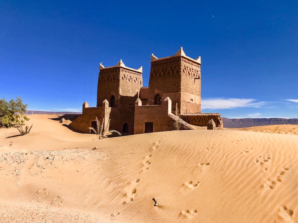 Edificio de hormigón marrón en el desierto bajo el cielo azul durante el día