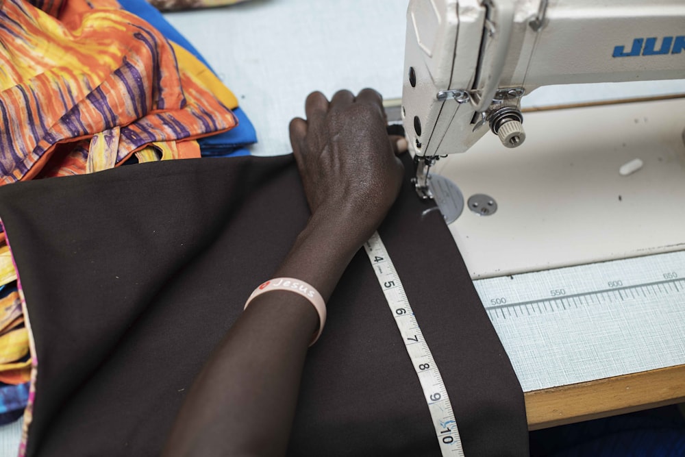 person in black shirt and black pants playing sewing machine