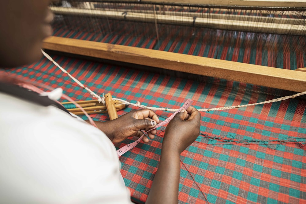 person in white pants lying on red and white hammock