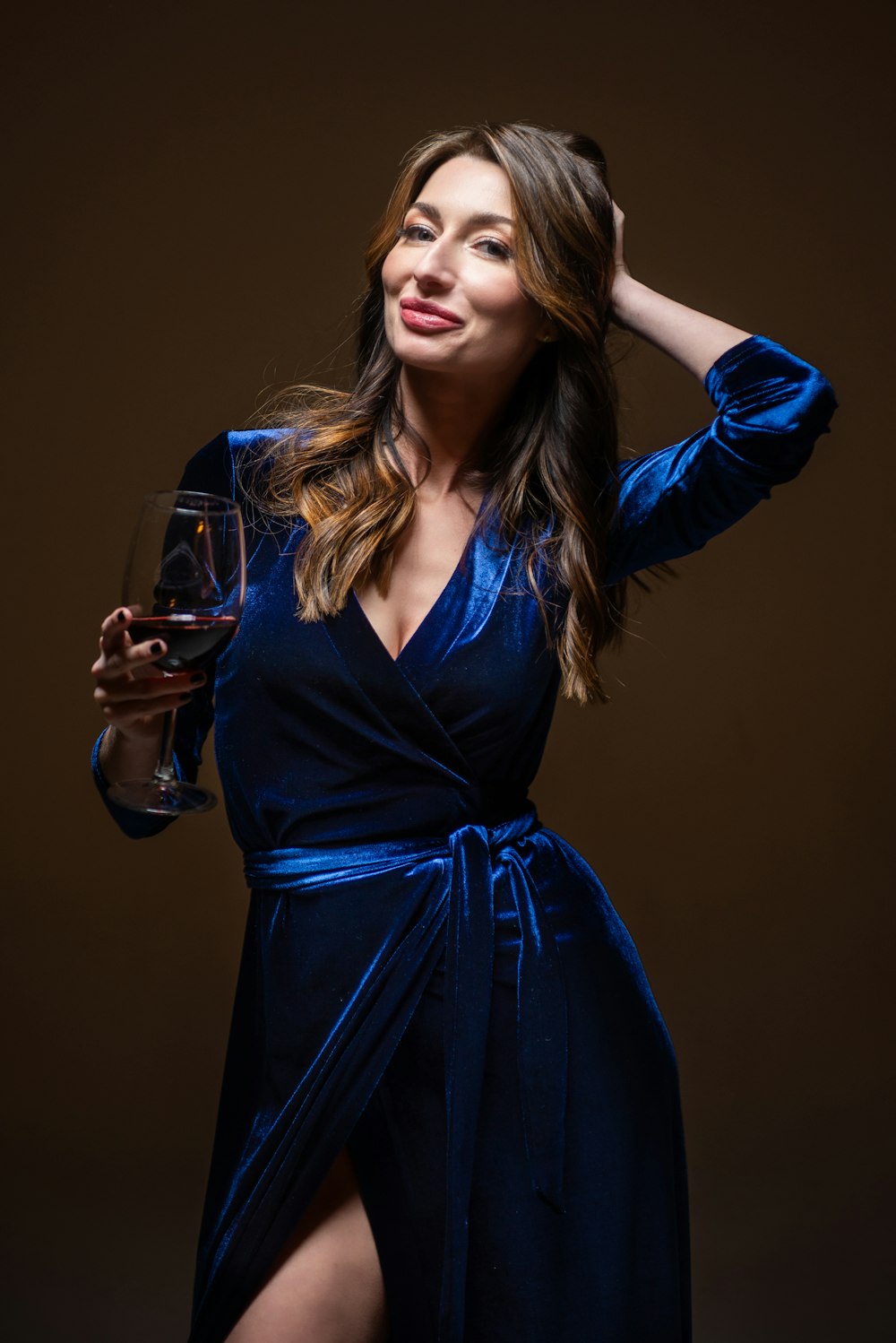 uma mulher em um vestido azul segurando um copo de vinho