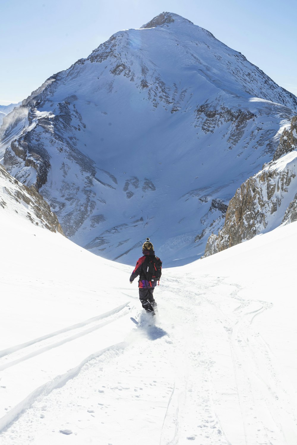 man in black jacket and black pants walking on snow covered mountain during daytime