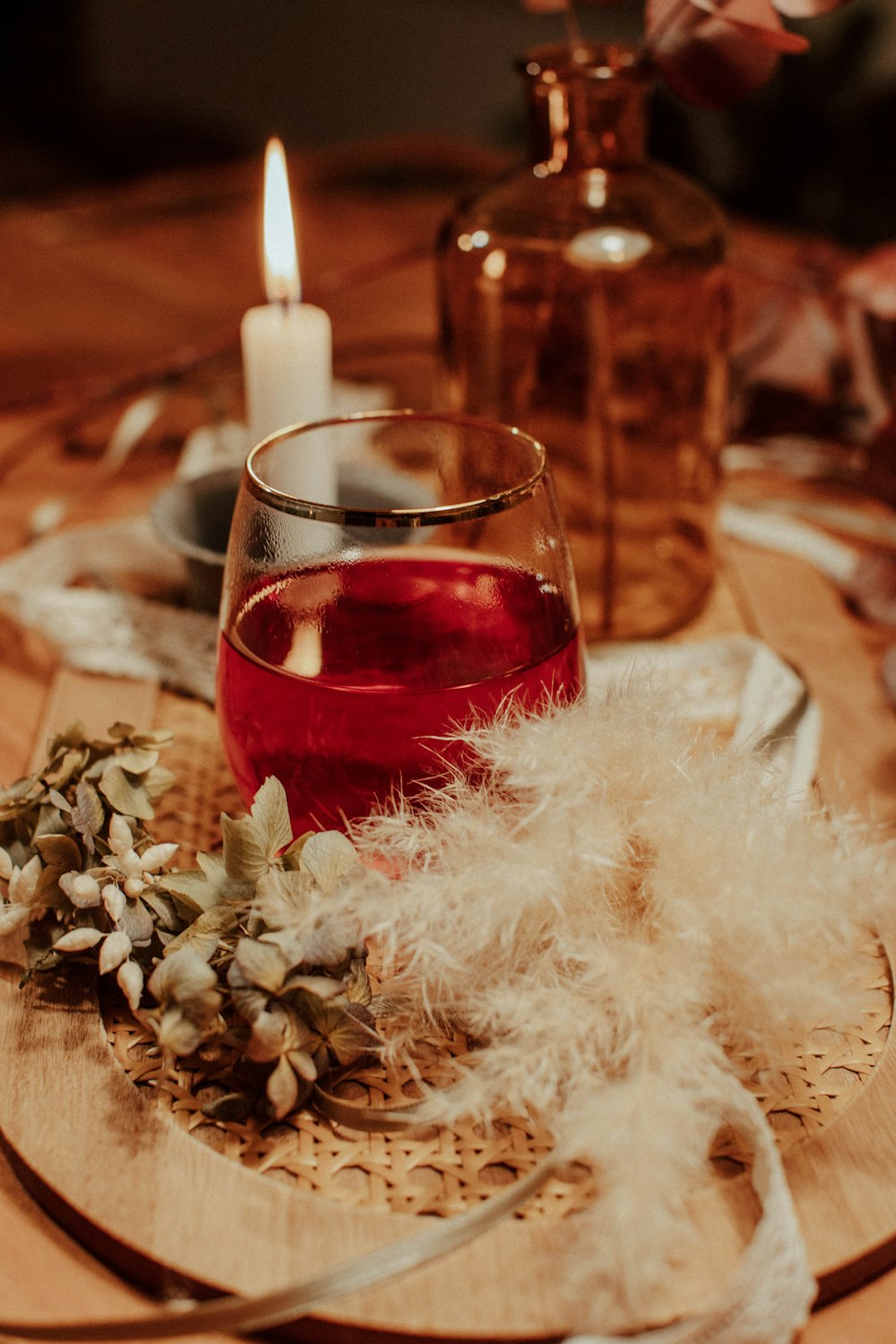 clear drinking glass with red liquid on brown wooden table