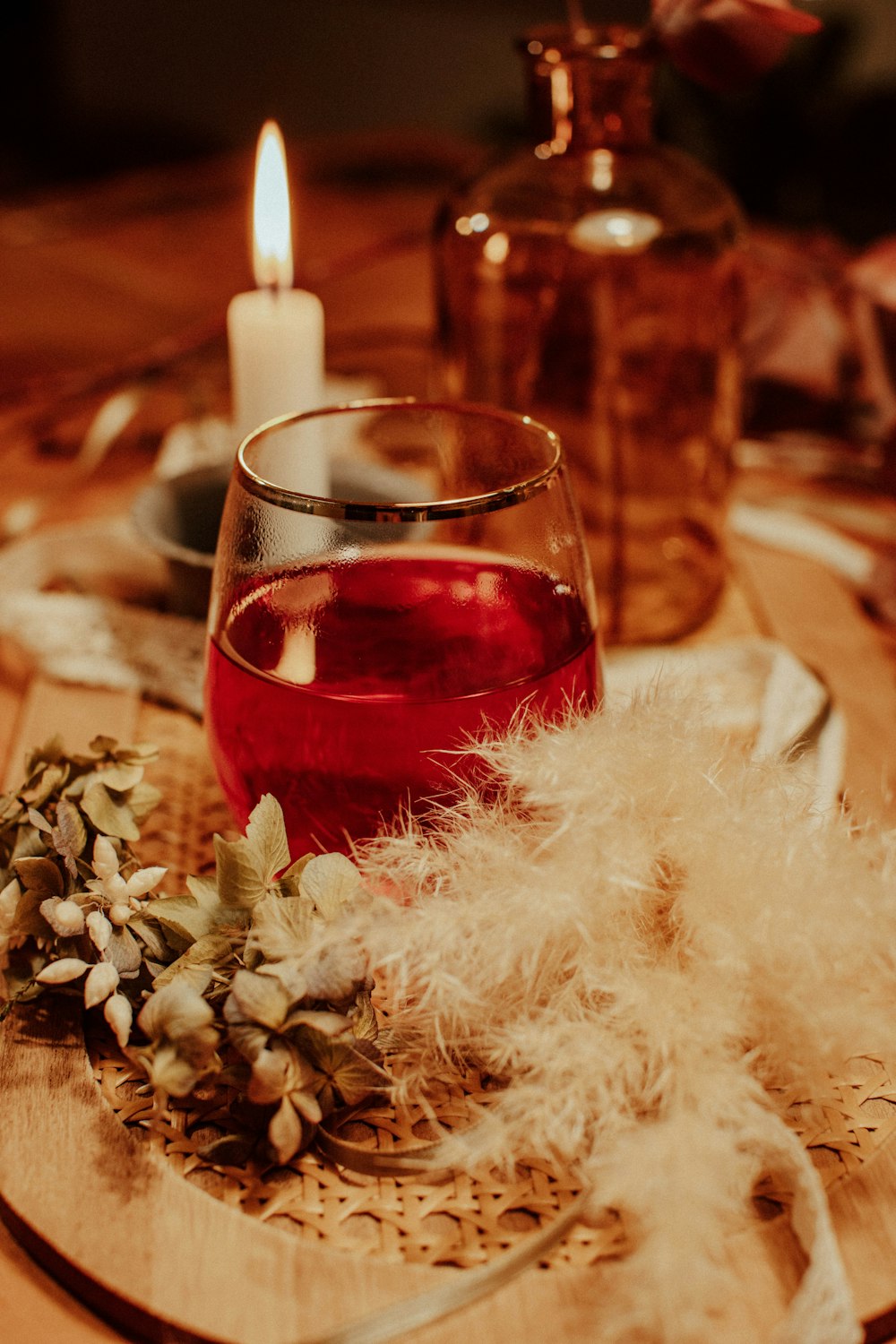 clear drinking glass with red liquid on brown wooden table