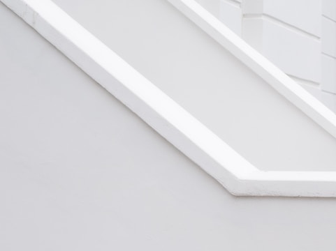A minimalist architectural detail with clean lines and a monochromatic palette, featuring angular shapes and smooth surfaces.