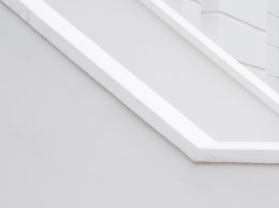 A minimalist architectural detail with clean lines and a monochromatic palette, featuring angular shapes and smooth surfaces.