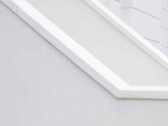 A minimalist architectural detail with clean lines and a monochromatic palette, featuring angular shapes and smooth surfaces.