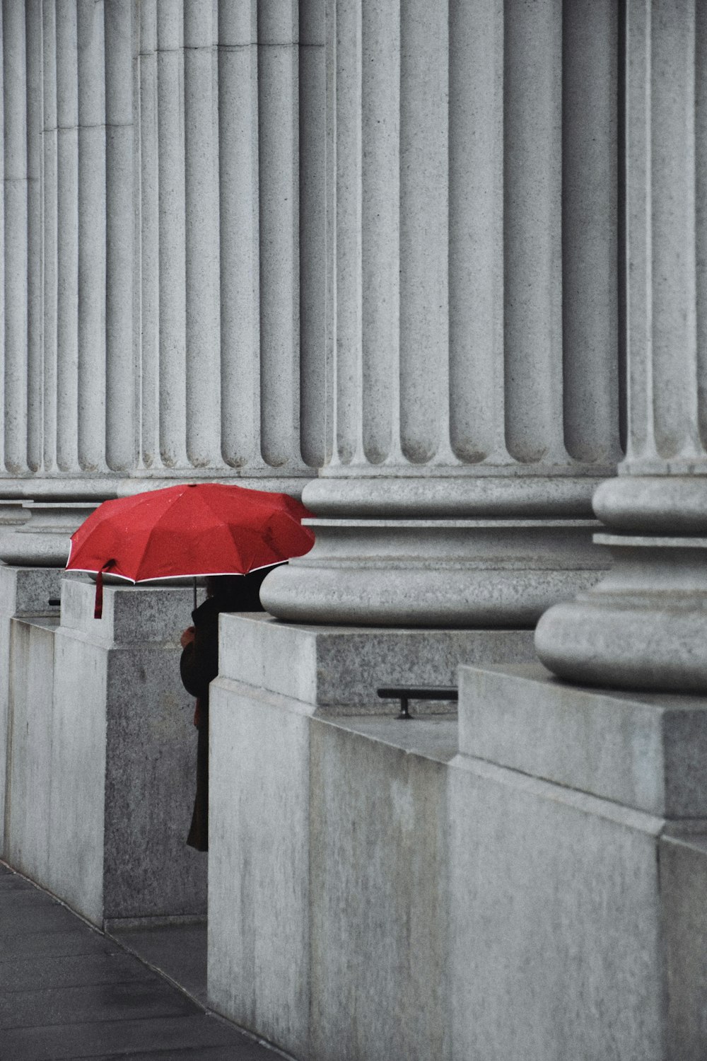 회색 콘크리트 기둥에 빨간 우산