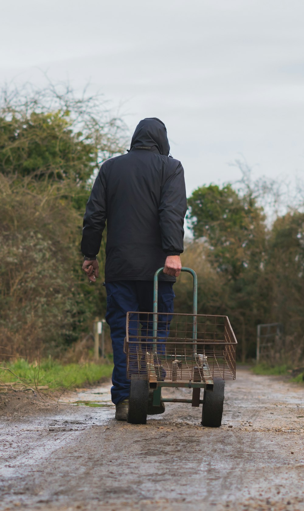 hombre con sudadera con capucha negra y jeans de mezclilla azul montando carrito de compras azul