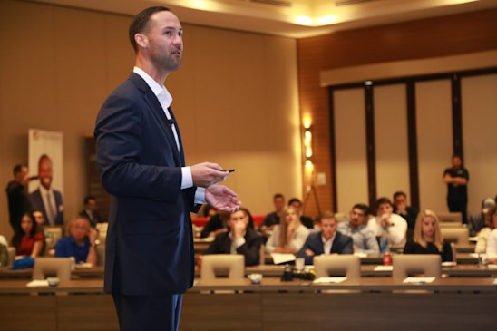 man in black suit standing on brown wooden floor