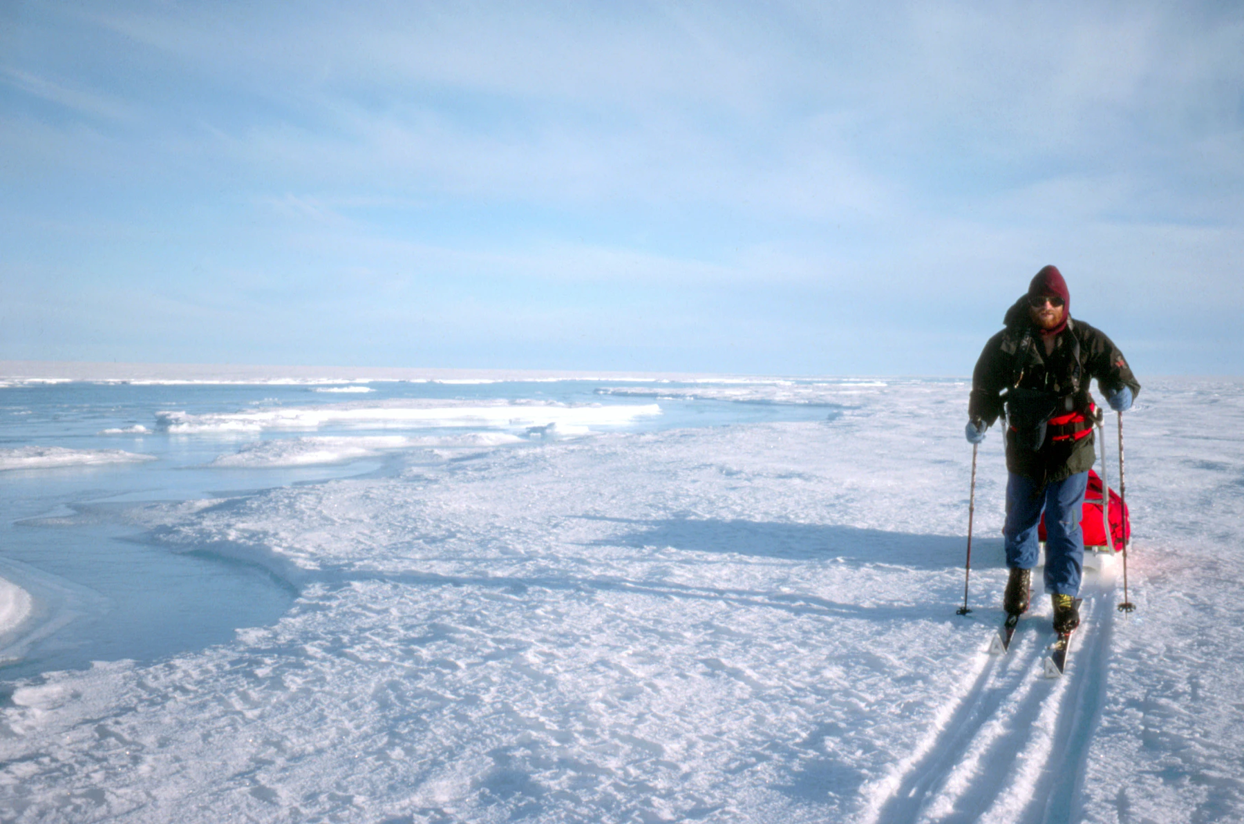 A distant anonymous figure walking across snow-covered ground