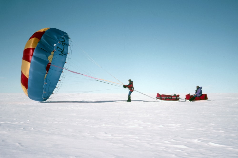 people riding on blue and yellow parachute during daytime