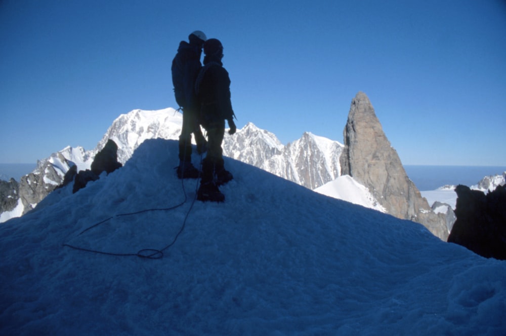 man in black jacket and pants standing on snow covered mountain during daytime