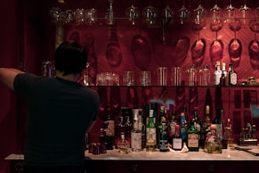 man in black shirt standing in front of bottles
