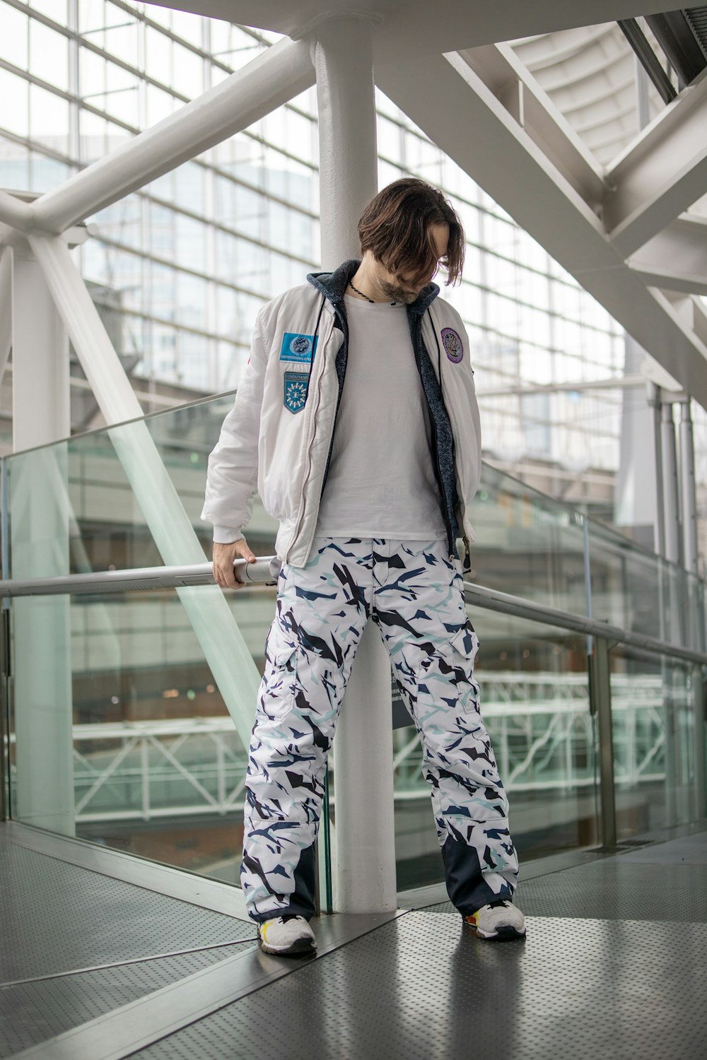 woman in white jacket and blue pants standing on gray metal railings