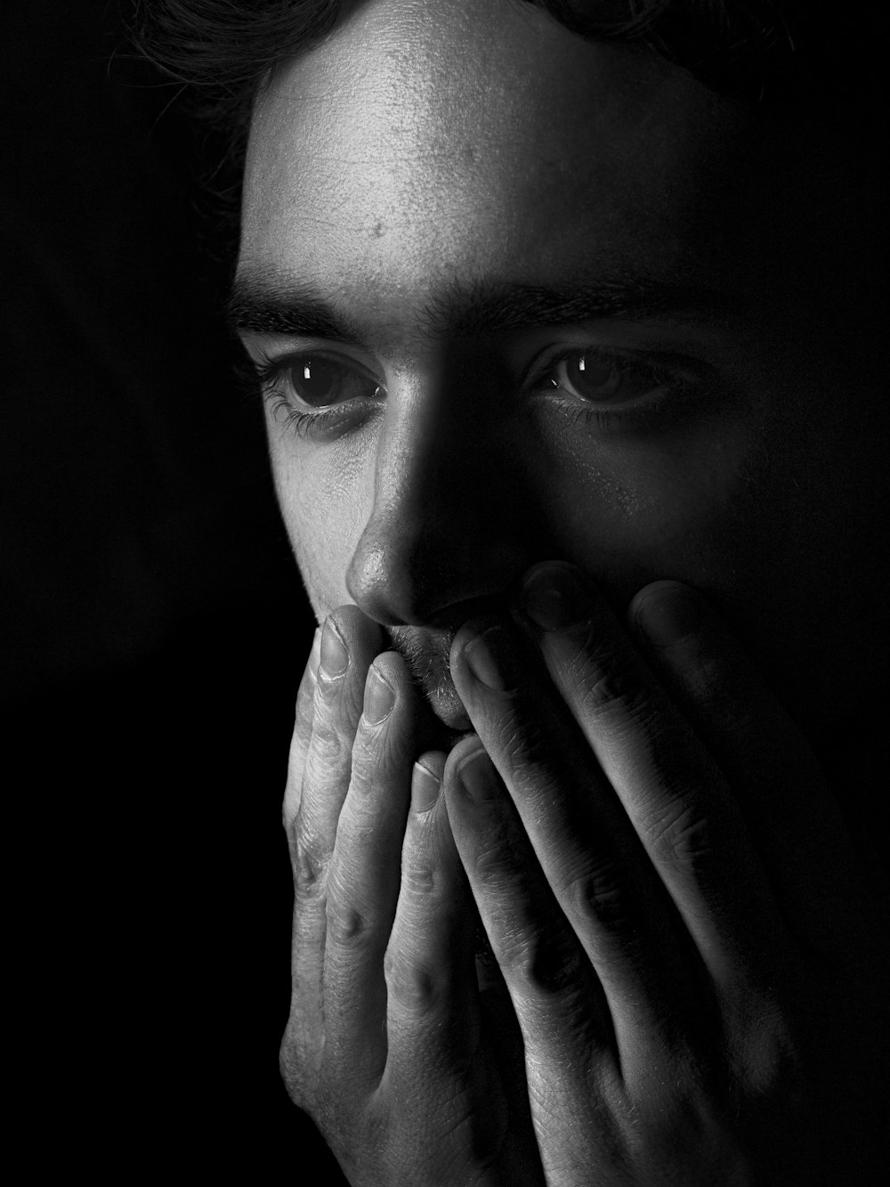 grayscale photo of woman covering her face with her hand