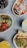 An assortment of colorful food items arranged in bowls on a textured surface. Each dish features fresh ingredients such as fruits, vegetables, and grains with vibrant toppings. Beverages accompany the dishes, enhancing the display with various colors.