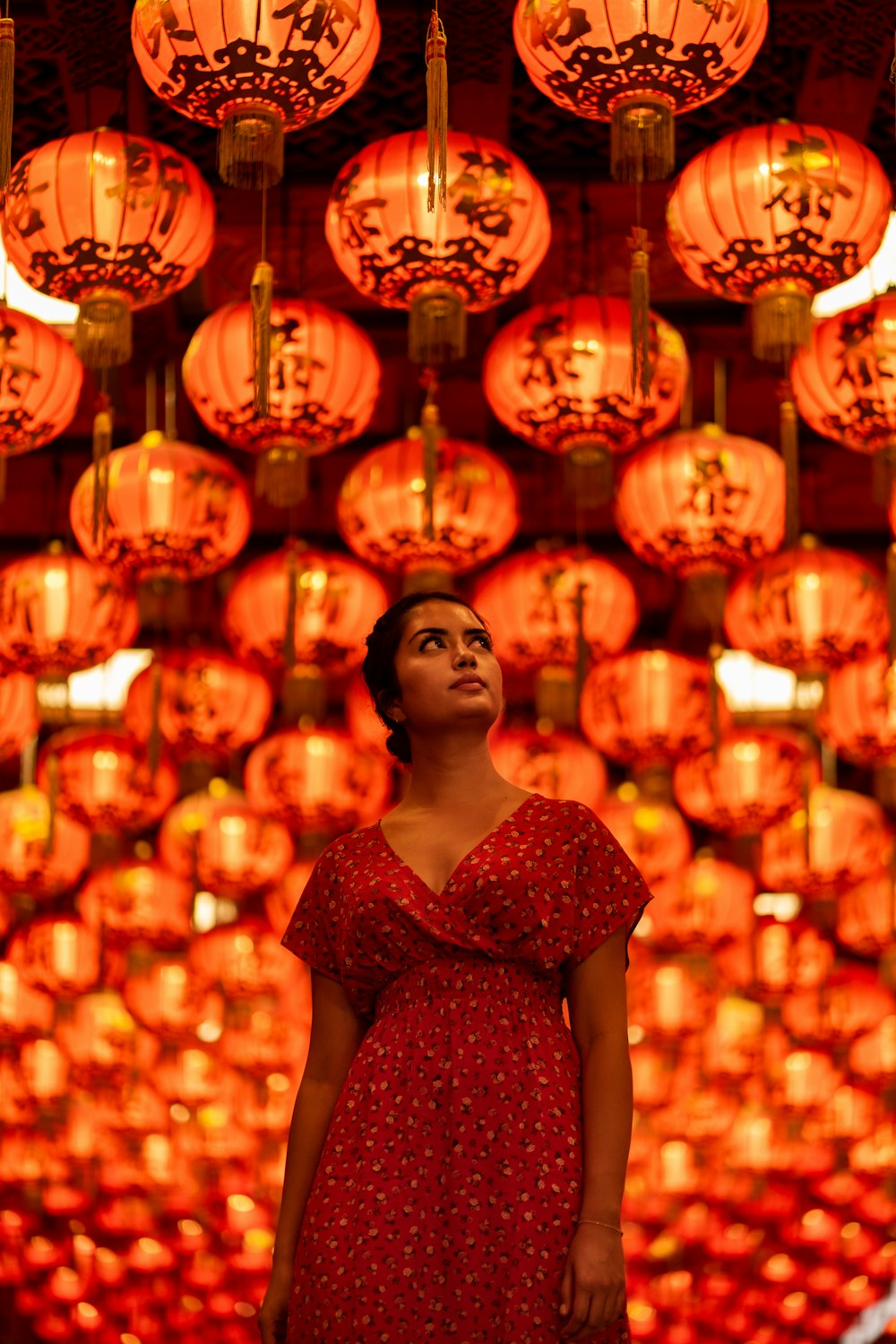 woman in red floral dress standing near lighted candles