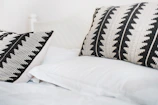 Close-up of a fluffy pillow with a modern geometric pillowcase in a bright, airy bedroom.