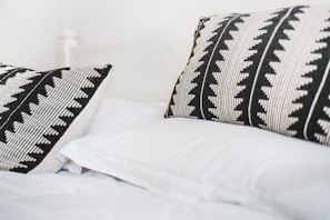 A plush pillow with a bold geometric print resting on a minimalist bed.