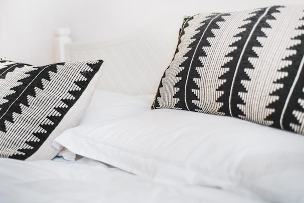 Close-up of a sleek, contoured ergonomic pillow resting on a minimalist white bed.