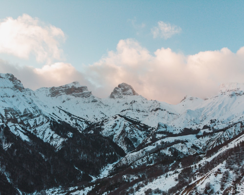 snow covered mountains under cloudy sky during daytime