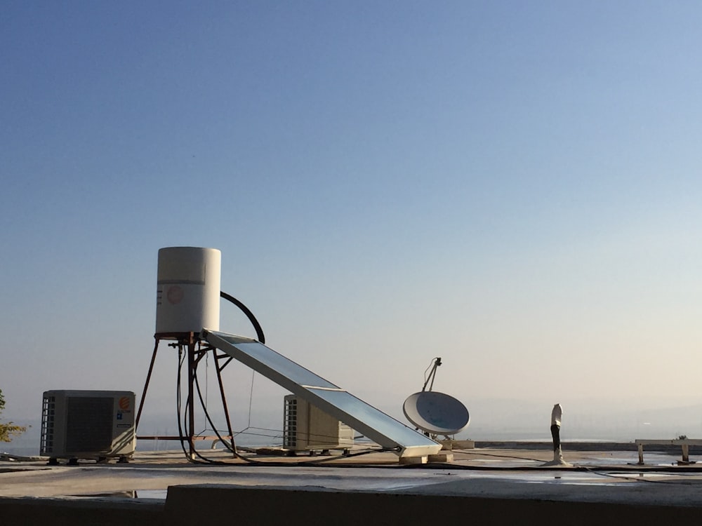 Antena parabólica blanca sobre piso de concreto gris durante el día