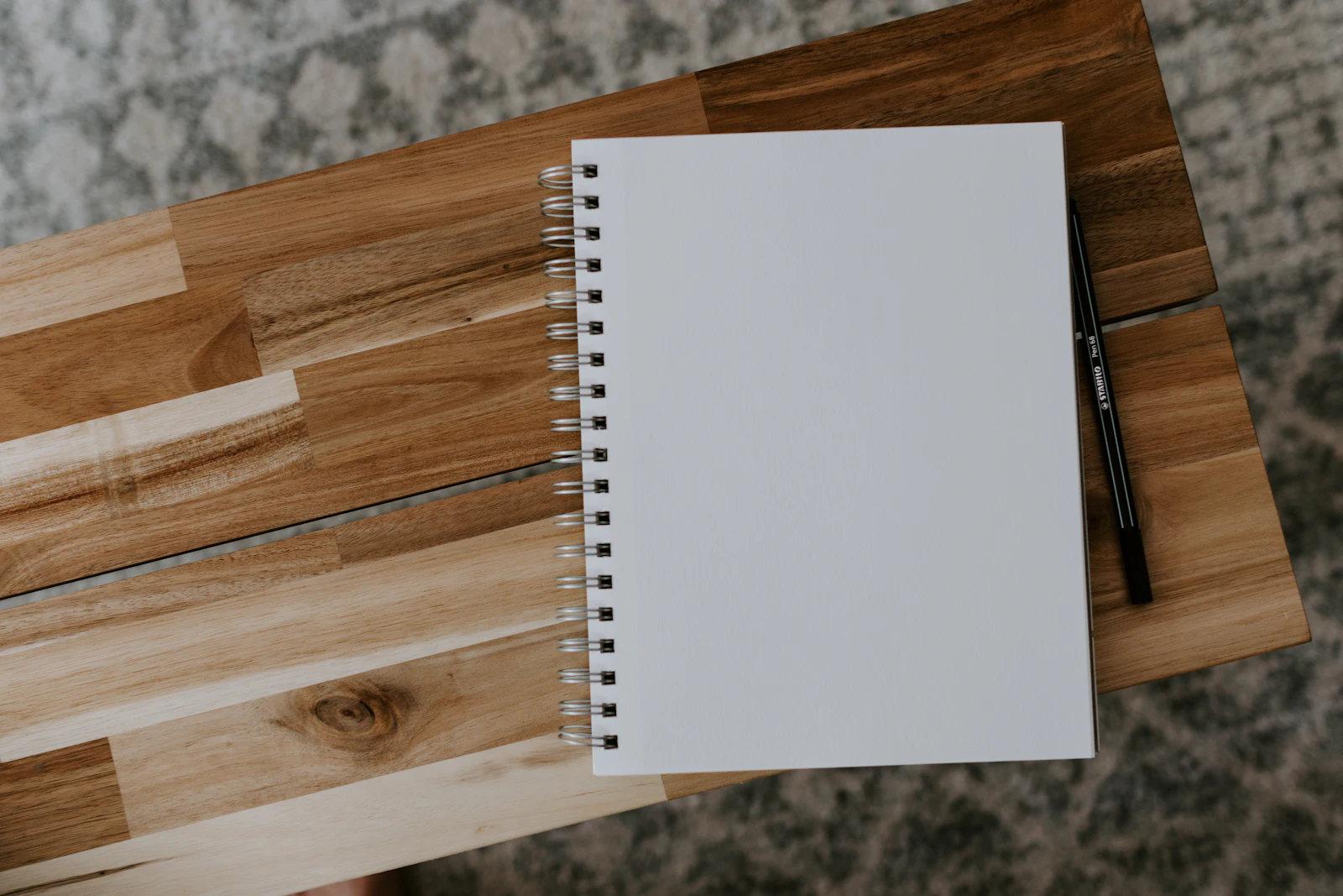 A white spiral notebook on a wooden table