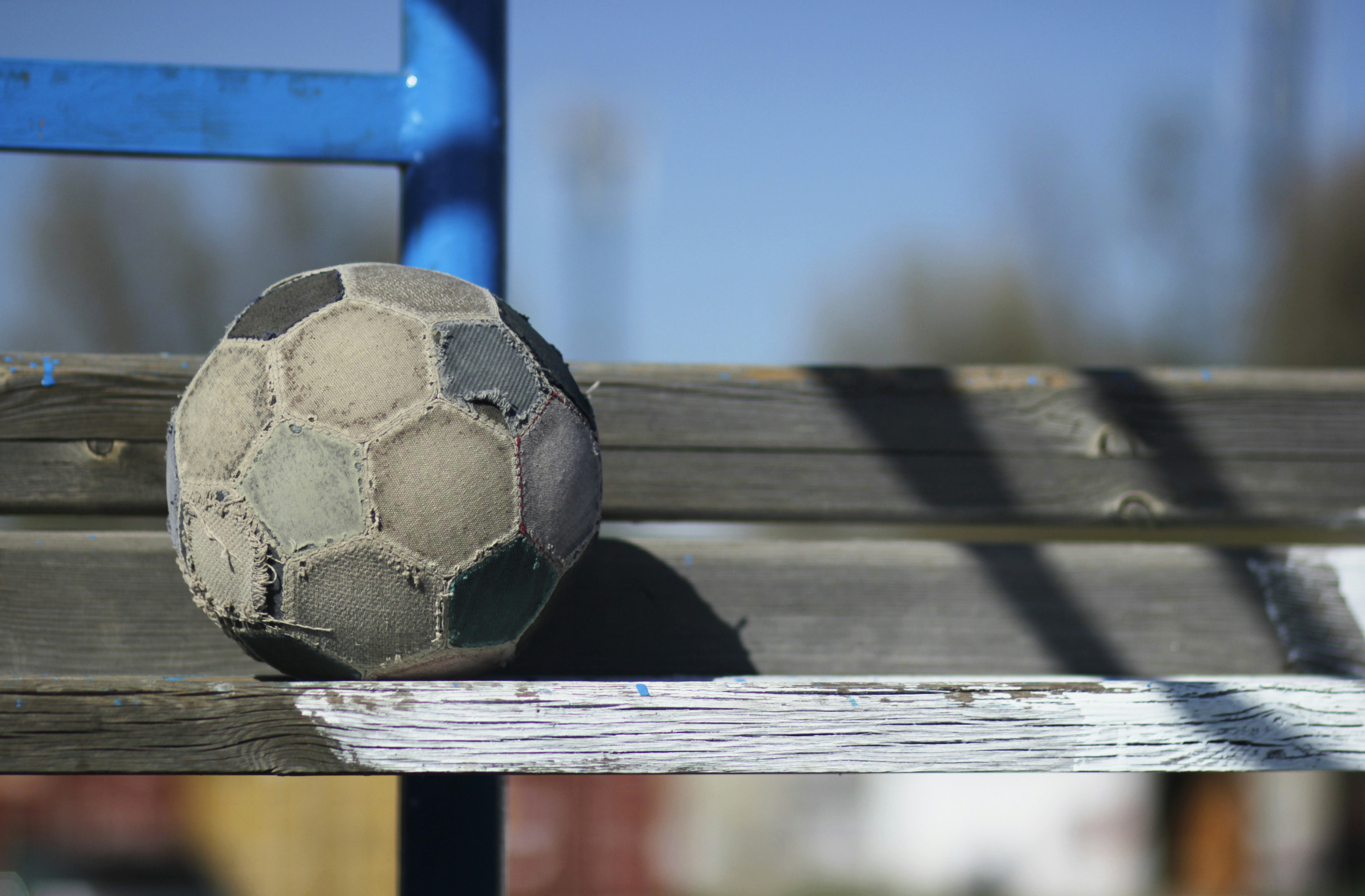 A worn-out football on a wooden bench.