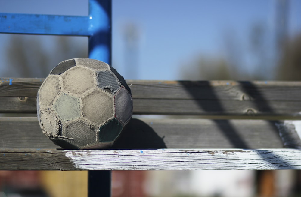black and white soccer ball on brown wooden plank