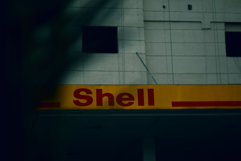 a shell gas station sign with a building in the background