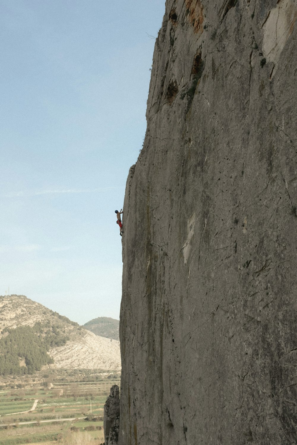 person in red shirt climbing on brown mountain during daytime
