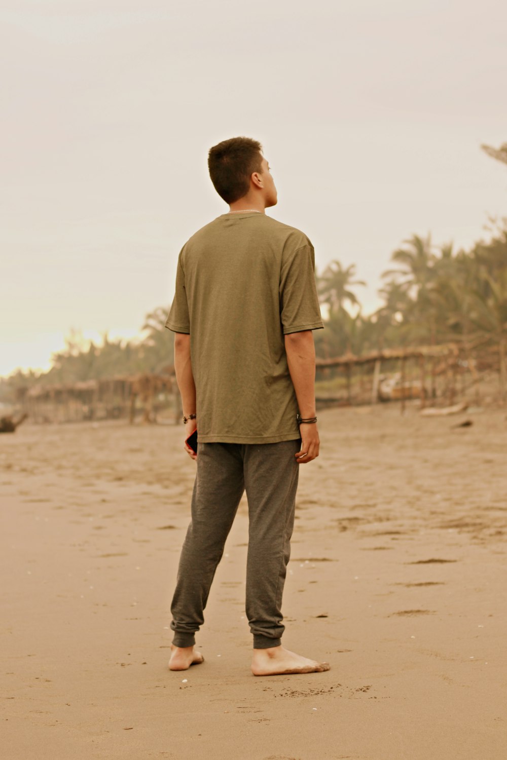茶色のTシャツと黒いズボンを着た男が昼間、茶色の砂の上を歩く