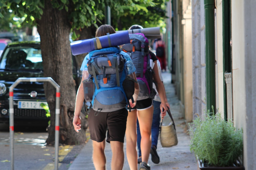 woman in blue and black backpack and black shorts with blue backpack walking on sidewalk during