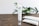 A tube of skincare cream labeled 'CRYSTALWEED High Quality CBD' is prominently displayed on a wooden surface. In the background, there are green leaves, adding a natural element to the setting. Additional tubes lie on the surface, slightly out of focus.