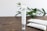 A tube of skincare cream labeled 'CRYSTALWEED High Quality CBD' is prominently displayed on a wooden surface. In the background, there are green leaves, adding a natural element to the setting. Additional tubes lie on the surface, slightly out of focus.