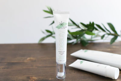 Close-up shot of a natural CBD-infused cosmetic product beside green hemp leaves, evoking freshness and purity.