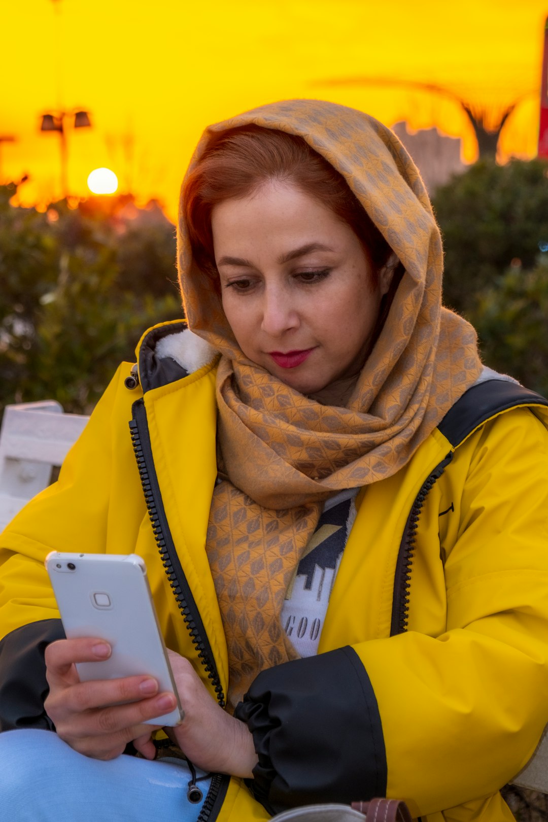 woman in yellow and blue jacket holding silver iphone 6