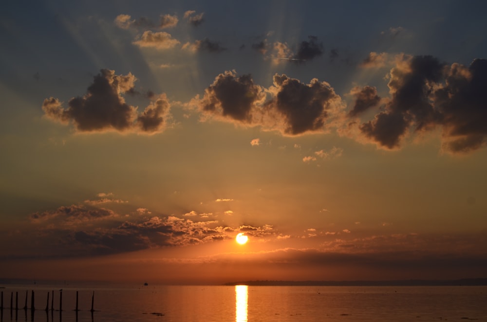 body of water under cloudy sky during sunset