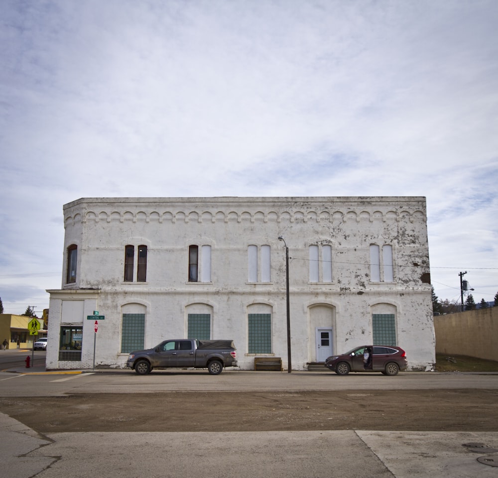 cars parked in front of white concrete building during daytime