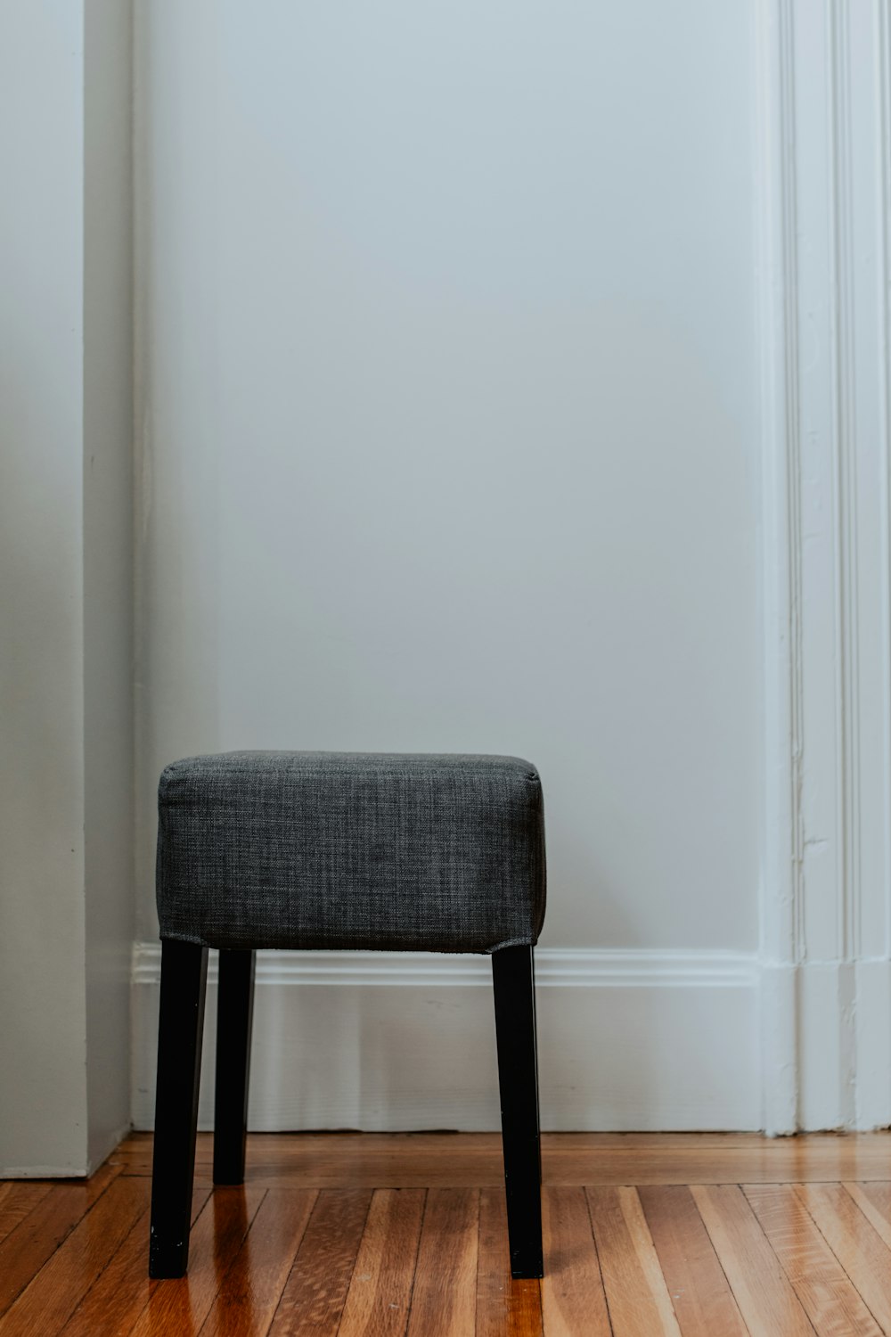 gray and black chair beside white wall