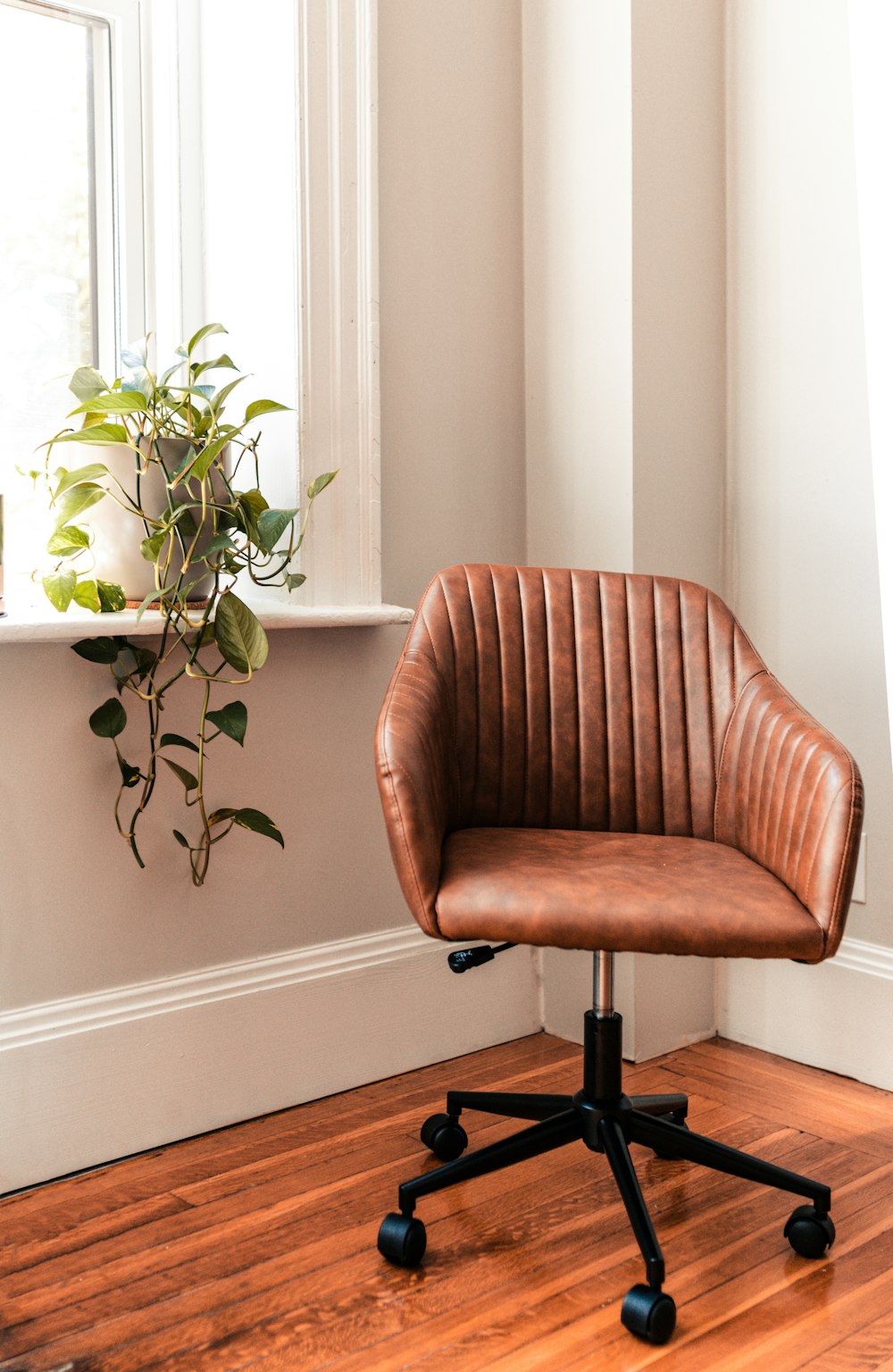 brown and black rolling chair beside green plant