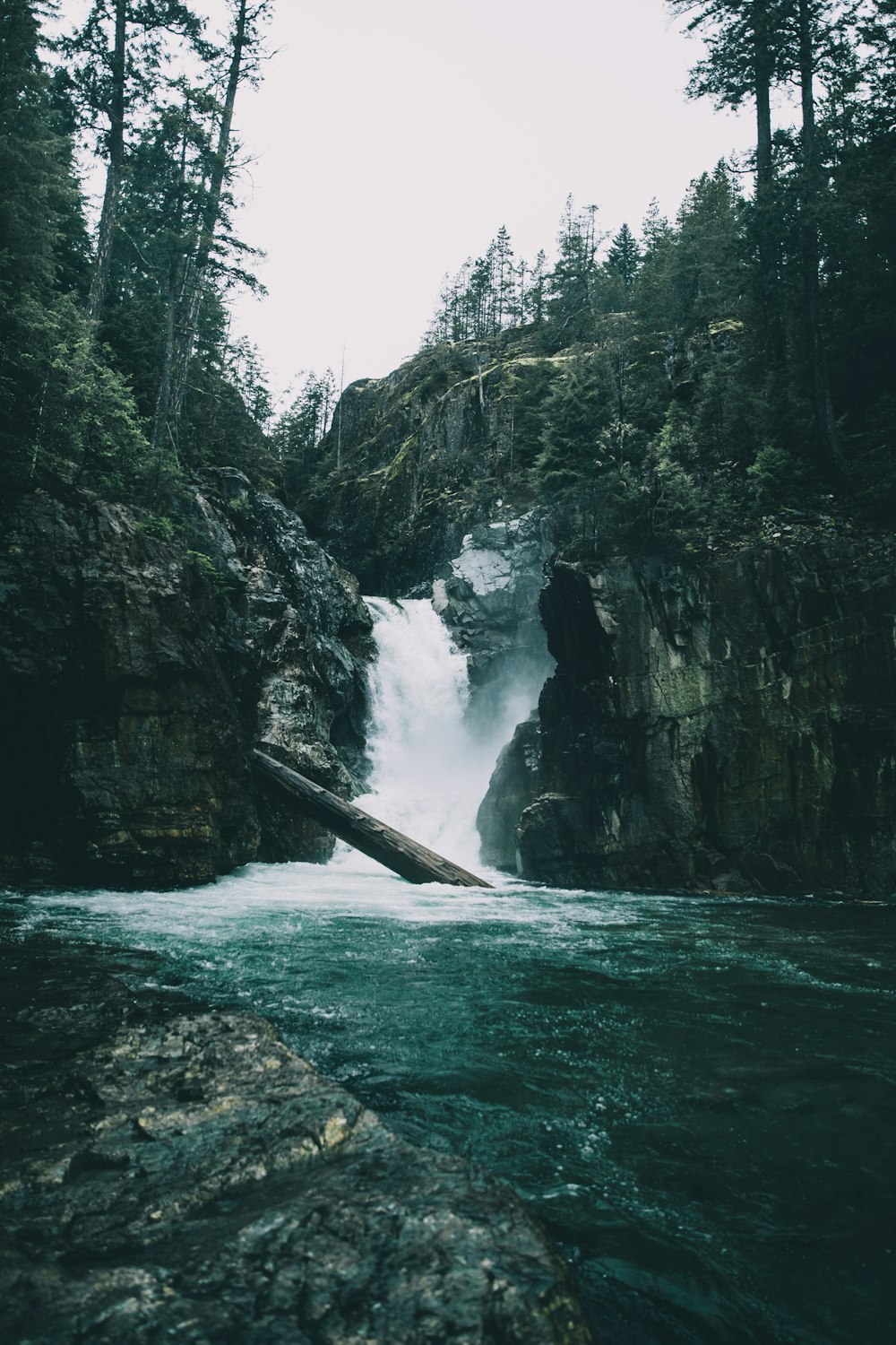 water falls between rocky mountain during daytime